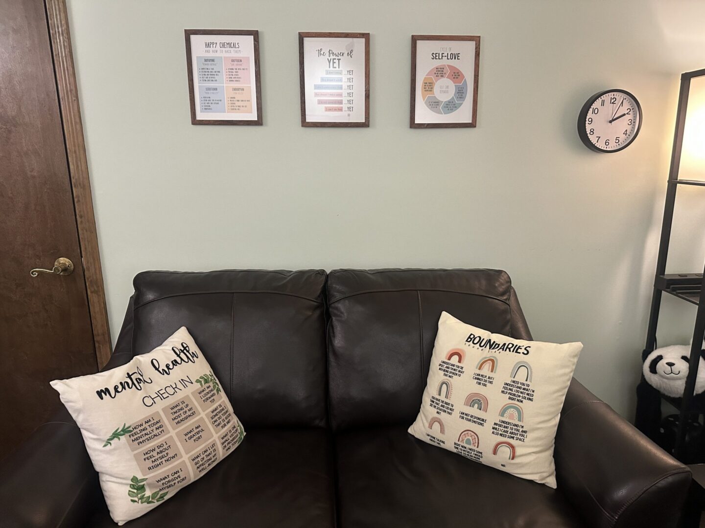 Leather couch with pillows under framed posters